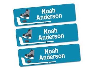 Peut inclure: Trois étiquettes de nom sur le thème du hockey, bleues et blanches, avec le nom "Noah Anderson" imprimé sur chaque étiquette.