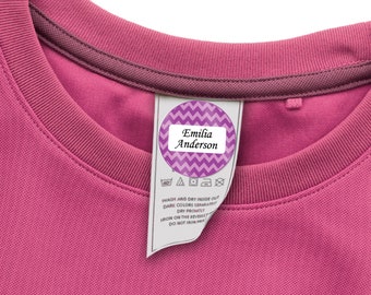 May include: A pink t-shirt with a purple and white chevron patterned iron-on label that says "Emilia Anderson".