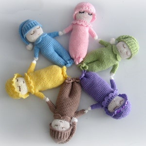 Peut inclure: Six poupées en crochet de différentes couleurs, disposées en forme d'étoile. Les poupées portent des vêtements de nuit et ont des yeux et une bouche brodés.