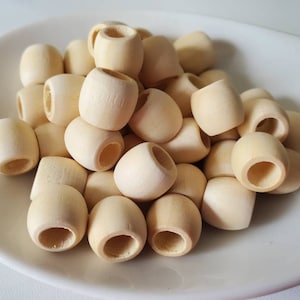 May include: A pile of natural wood beads, each with a hole in the center. The beads are round and smooth, and they are all the same size.