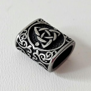 May include: A silver-toned metal bead with a Celtic knot design. The bead has a rectangular shape and is decorated with intricate floral patterns.