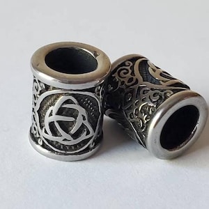 May include: Two silver metal beads with intricate Celtic knot designs. The beads are cylindrical and have a smooth, polished finish.