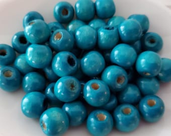 May include: A pile of teal blue wooden beads. The beads are round and have a hole in the center.