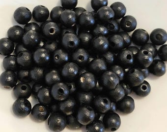 May include: A large pile of black wooden beads. The beads are round and have a smooth, polished finish.