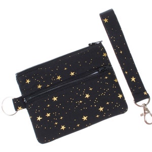 May include: Black zippered pouch with a gold star pattern and a matching black strap with a silver clip.
