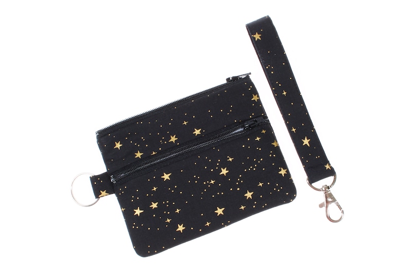 May include: Black zippered pouch with a gold star pattern and a matching black strap with a silver clip.