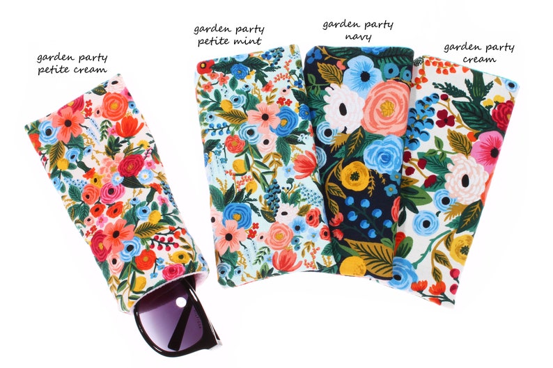 May include: Four floral patterned eyeglass cases in cream, mint, navy, and cream. The cases are lined up horizontally with the cream case on the right and the mint case on the left. A pair of sunglasses is partially visible in the cream case.