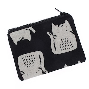 May include: Black zippered pouch with a repeating pattern of stylized gray cats. The cats have simple facial features and are set against a black background. The pouch is rectangular and has a black zipper.