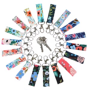 May include: A collection of 18 colorful floral patterned keychains with silver key rings. The keychains are arranged in a circle with two keys in the center.