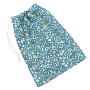 May include: Teal drawstring bag with a floral pattern in shades of pink, blue, and gold. The bag is made of fabric and has a white drawstring.