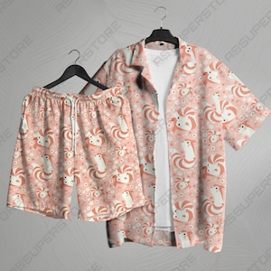 May include: A pink and white patterned short-sleeved shirt and matching shorts set. The shirt has a button-up collar and a relaxed fit. The shorts have an elastic waistband and a drawstring.