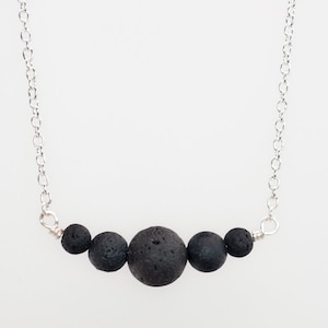 May include: A silver chain necklace with five black lava rock beads.