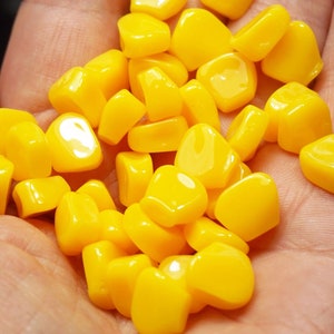 May include: A close-up of a handful of yellow corn kernels.