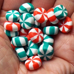 May include: A handful of colorful candies in red, white, and green. The candies are round and striped, with a pinwheel design. Some are cylindrical. The image is a close-up shot.