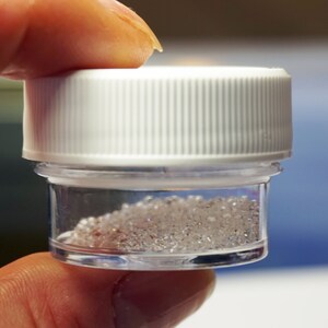May include: A small clear plastic jar with a white lid filled with clear, shiny crystals.