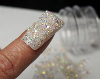 May include: A fingernail with a clear base and a design of iridescent rhinestones.