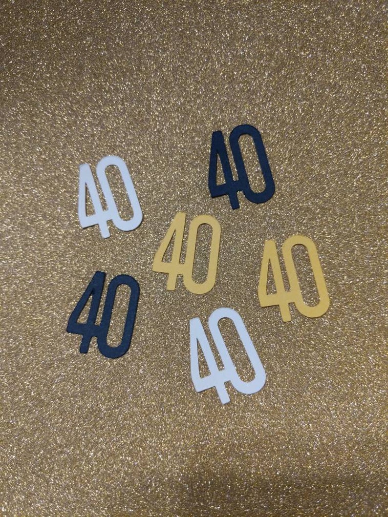 May include: Six paper cutouts of the number "40" in different colors. There are two black, two white, and two gold cutouts.