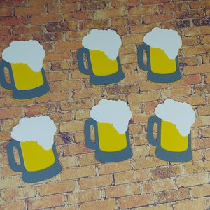 May include: Six paper cutouts of beer mugs with white foam on top. The mugs are gray with yellow beer inside. The cutouts are arranged in two rows of three on a brick wall background.