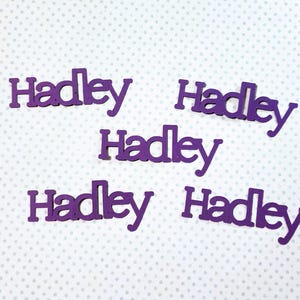 May include: Five purple wooden cutouts of the name "Hadley".