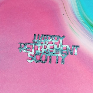 K&ouml;nnte beinhalten: Happy Retirement Scotty in silbernen Glitzerbuchstaben auf rosa Hintergrund.