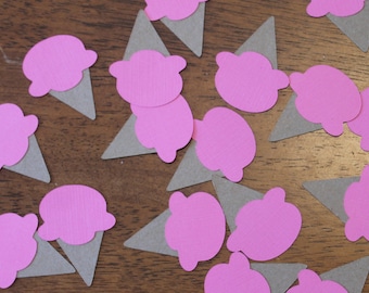 May include: Pink and gray paper ice cream cone cutouts. The ice cream cones are scattered on a wooden surface.