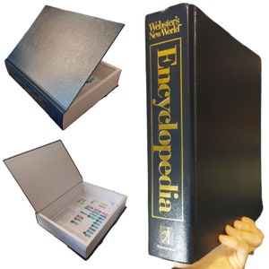 May include: A black, hardcover book with the title "Webster's New World Encyclopedia" in gold lettering. The book is open to reveal a hidden compartment.