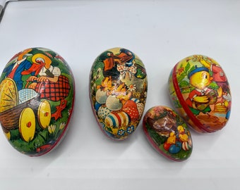 May include: Four vintage Easter egg-shaped boxes with colourful illustrations. The boxes feature images of chicks, ducks, and rabbits. The boxes are made of paper and have a red and white trim.