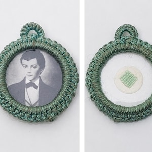 Peut inclure: Un pendentif circulaire avec une bordure en crochet vert et une petite boucle sur le dessus. Un côté présente un portrait en noir et blanc d'une personne en costume avec un nœud papillon. L'autre côté montre un centre transparent avec un petit carré cousu vert clair.