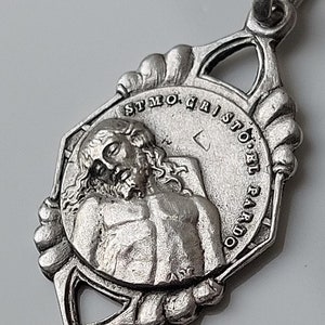 May include: Silver pendant with a detailed image of Jesus Christ and the text "ST.MO. CRISTO. DEL. PARDO" around the edge.