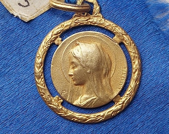 May include: Gold-toned pendant featuring a relief of the Virgin Mary with a halo, surrounded by a decorative wreath. The pendant has the inscription "ASSIERI" on the side.
