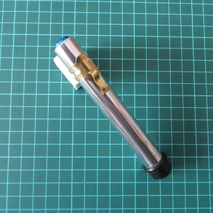 May include: A silver and gold metal pen with a blue cap and a black end cap. The pen is on a green cutting mat.