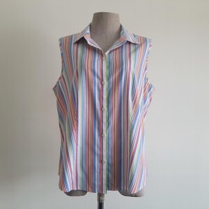 Op de afbeelding: Mouwloze blouse met verticale strepen in diverse kleuren, waaronder blauw, roze, geel en groen. De blouse heeft een kraag en een knoopsluiting. Gepresenteerd op een paspop. De stof is licht van gewicht.