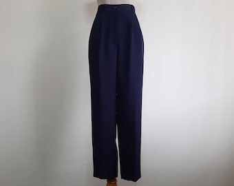 Puede incluir: Pantalones de talle alto en un color azul marino oscuro sólido. Estos pantalones presentan una cintura estructurada con un cierre de un solo botón, una cremallera frontal y un corte de pierna recta que llega hasta los tobillos.