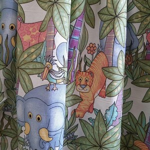 May include: Fabric with a jungle-themed pattern featuring cartoon animals like tigers, elephants, and giraffes. The design includes palm trees, flowers, and a bird. The color palette includes shades of green, orange, blue, and pink.