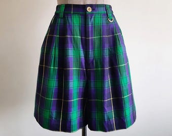 May include: High-waisted shorts featuring a vibrant green, purple, and black plaid pattern. The shorts include a button closure at the waistband, belt loops, and a small metal D-ring attached near the front pocket area.