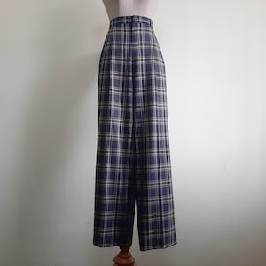 May include: Navy and beige plaid trousers on a mannequin. The high-waisted, wide-leg design features a classic plaid pattern. These trousers are suitable for various occasions. The fabric appears to be of medium weight, offering a comfortable fit.