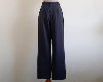 Puede incluir: Pantalones de talle alto en un color azul marino oscuro sólido. Estos pantalones presentan una silueta de pierna ancha, una cintura estructurada con cierre de un solo botón, cremallera frontal y pliegues sutiles bajo la cintura.