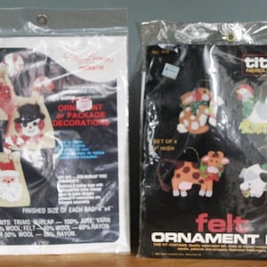 Könnte beinhalten: Zwei versiegelte Bastelsets. Eines zeigt Jutetaschen mit Feiertagsmotiven wie einem Schneemann und dem Weihnachtsmann. Das andere ist ein Filz-Ornament-Kit mit Tierformen. Die Texte lauten "Ornament or Package Decorations" und "Felt Ornament Kit".