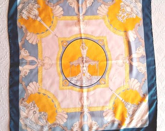 May include: Square silk scarf with a navy blue border. The scarf features a central design of a fountain within a yellow circle, surrounded by ornate details in shades of peach, yellow, and blue. The words "Fontane di Roma" are visible.