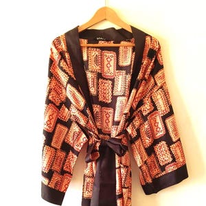 May include: A black silk robe with a patterned design of orange and red squares. The robe has a black satin sash.