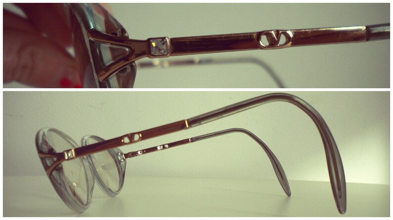 May include: A pair of gold-toned eyeglasses with a clear frame and lenses. The glasses have a double bridge and a thin metal arm.
