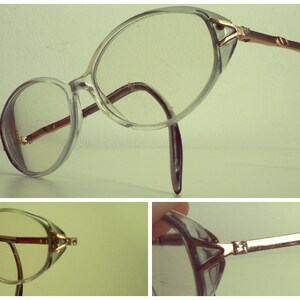 May include: Clear plastic framed glasses with gold metal accents and a brown plastic temple. The glasses have a cat-eye shape.