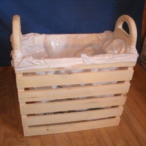 May include: A wooden crate with a plastic liner, perfect for storing items or as a trash can. The crate has a natural wood finish and is made of sturdy wood.