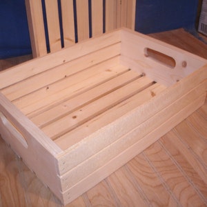 May include: A natural wood crate with two handles. The crate is empty and has a light wood finish.