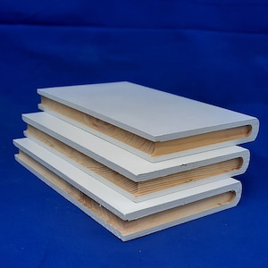 May include: A stack of three white books with wooden edges. The books are stacked on top of each other, with the top book being the largest and the bottom book being the smallest.