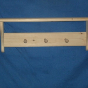 May include: A wooden shelf with four knobs for hanging items. The shelf is made of natural wood and has a simple design.