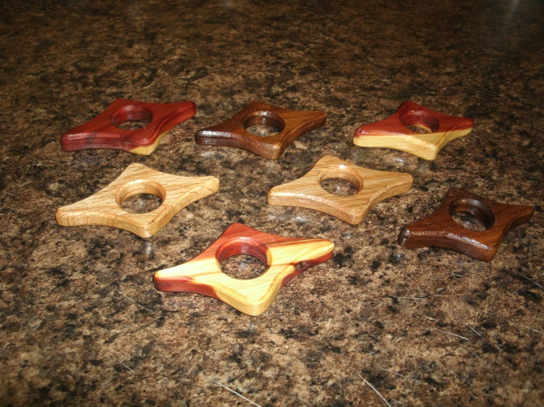 Puede incluir: Ocho sujetalibros de madera con forma de estrella y un agujero en el centro. Los sujetalibros est&aacute;n hechos de diferentes tipos de madera, incluyendo cedro, nogal y arce. Los sujetalibros son de diferentes colores, incluyendo marr&oacute;n, rojo y amarillo.