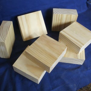 May include: A collection of six unfinished light-colored wooden blocks with visible grain patterns. Each block is rectangular in shape with smooth, flat surfaces and sharp edges, arranged in a cluster to display the natural texture of the wood.