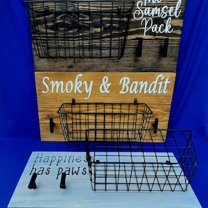 Puede incluir: Un organizador de pared de madera con tres cestas de alambre y el texto "The Samsel Pack", "Smoky & Bandit" y "Happiness has paws".