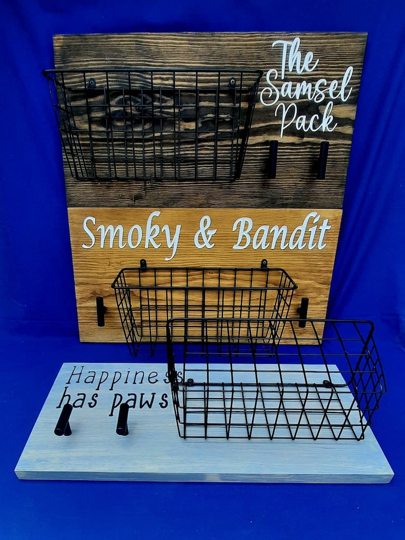 Puede incluir: Un organizador de pared de madera con tres cestas de alambre y el texto "The Samsel Pack", "Smoky & Bandit" y "Happiness has paws".